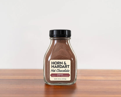 A glass bottle of Horn and Hardart Hot Chocolate sitting on a wooden table.