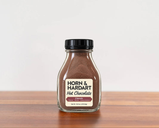 A glass bottle of Horn and Hardart Hot Chocolate sitting on a wooden table.