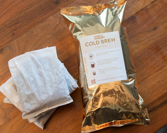 Gold foil package of cold brew coffee on a wooden surface with white packets.