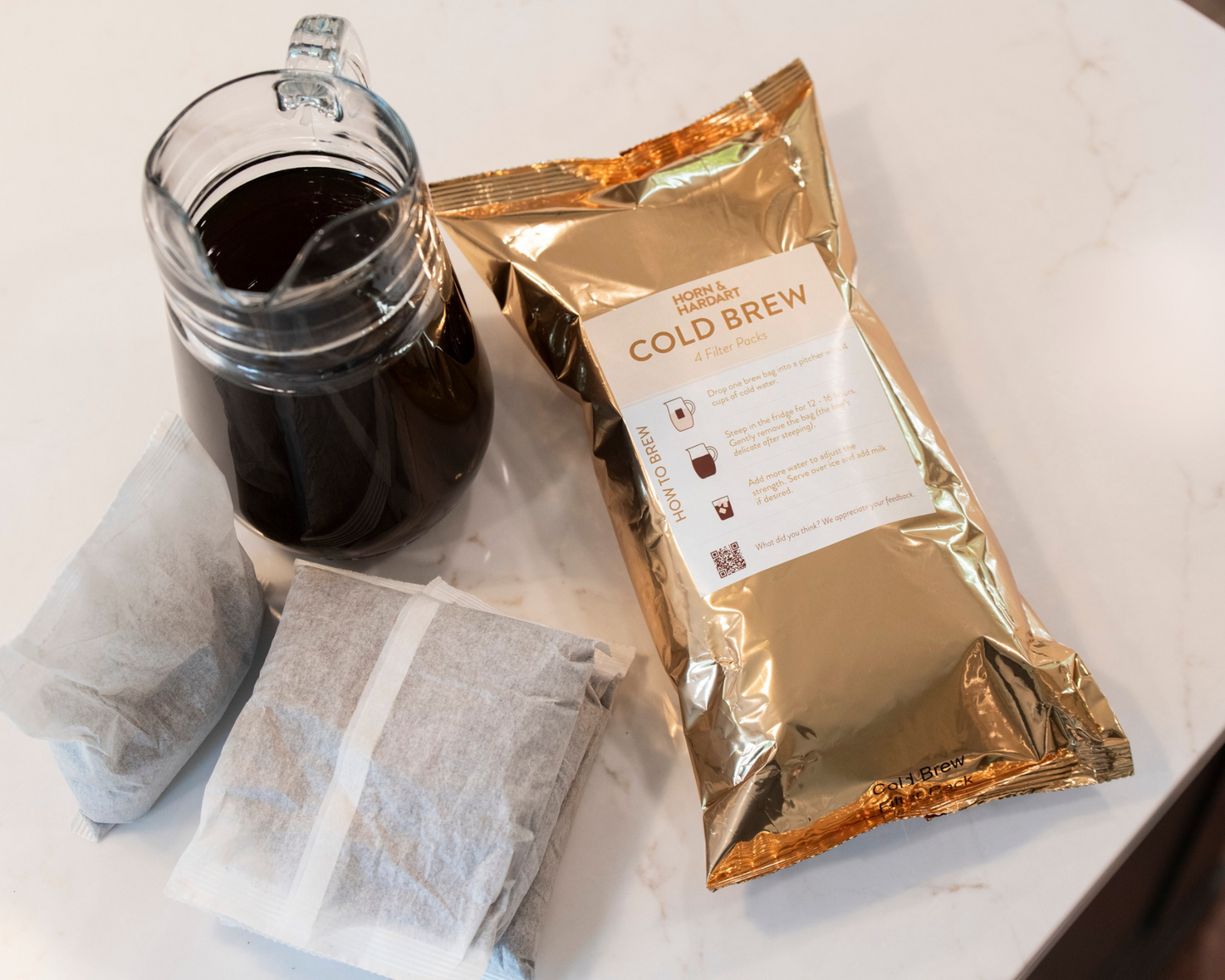 Cold brew coffee package with a jar of coffee and filter on a white surface