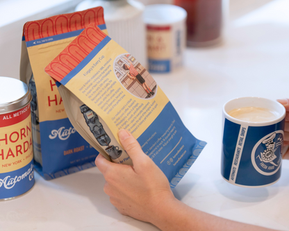 Hand holding bag of Automat Coffee and blue mug.